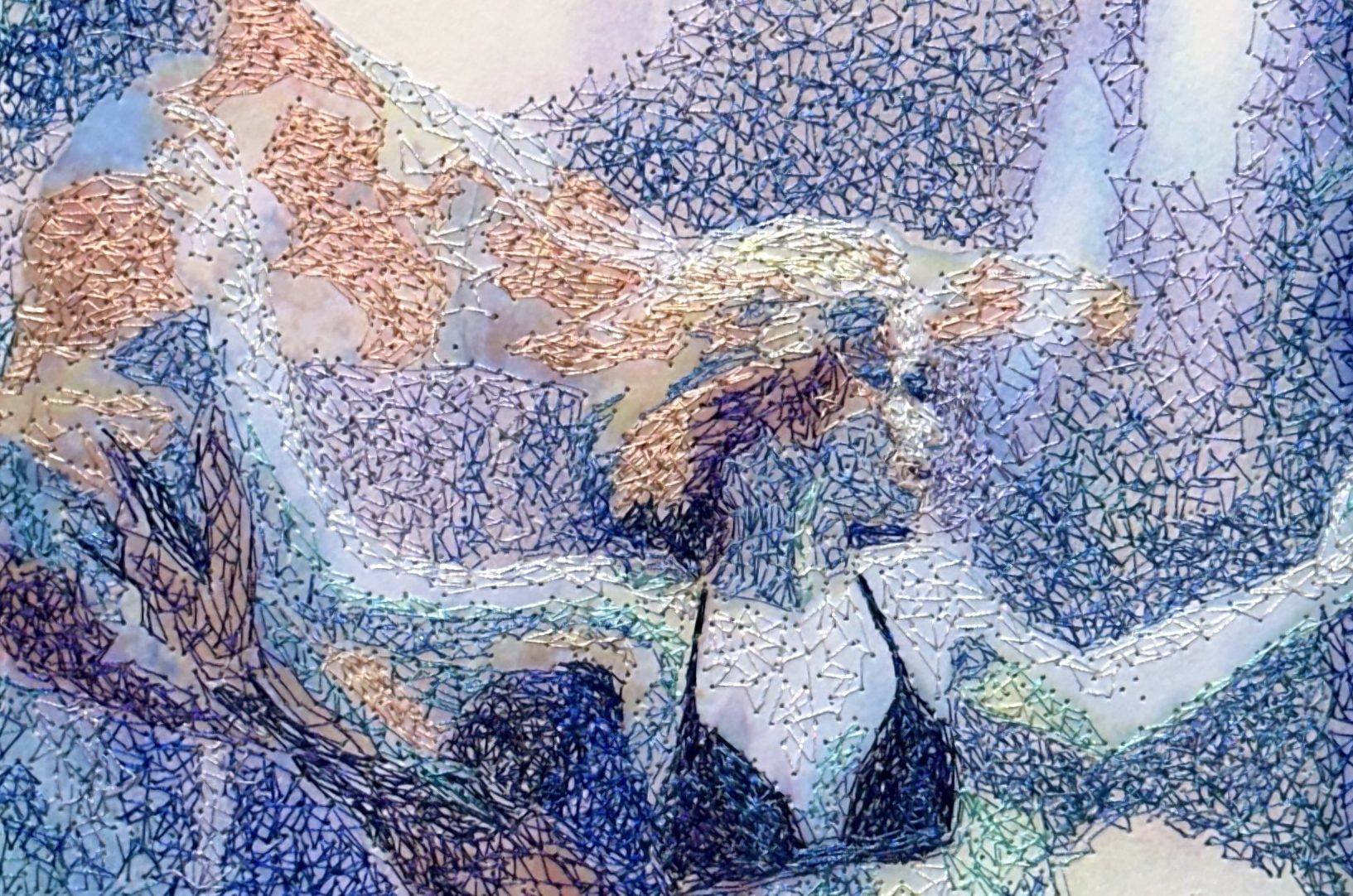 A stitched swimmer in a dark bikini surrounded by blue, violet and peach thread